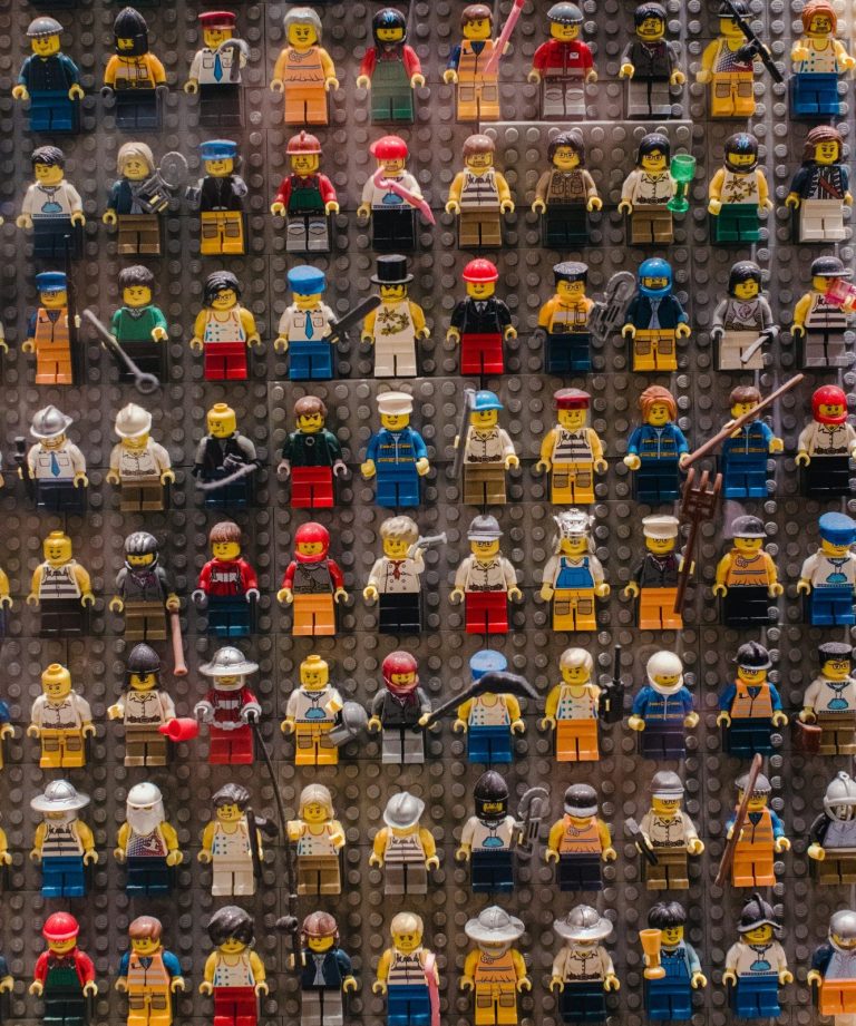 80 + Lego characters stuck onto a board and facing outwards towards the camera.